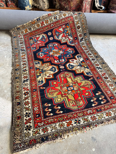 Antique 1920s Persian rug with bold geometric medallions.
