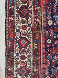 Decorative Persian rug with ivory border and colorful garden motifs.
