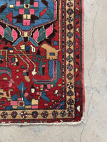 Corner view of Persian rug decorated with pinwheel of life border motifs.