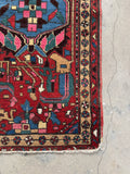 Corner view of Persian rug decorated with pinwheel of life border motifs.