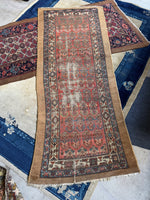 Full view of antique Persian runner with coral ground and paisley motifs.
