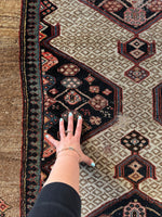 Persian rug with strong geometric medallion art and some scattered wear.