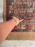 Handwoven antique Persian runner with lattice field and patch repair.