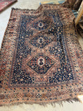 Full view of a 6’7 x 9’ Shiraz rug with rust and navy tones.