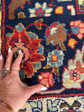 Hand-knotted Persian rug with low pile and scattered wear, showing age gracefully.