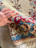 Blue and ivory Persian scatter rug with red and green floral details.
