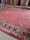 Hand-knotted 100-year-old Persian rug displaying intricate floral motifs and a rich, glowing wool texture.