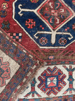 Underside view of antique tribal runner with raw wool fringes and symbolic patterns.