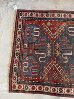 One end of Kazak rug with tribal motifs and aged dyes.