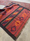 Antique Turkish tribal rug featuring bold graphic patterning, earthy wool tones, and a durable flatwoven handle.
