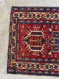 One end view of vintage Persian Heriz rug in red, navy, and wheat tones, sized approximately 3' x 5'.