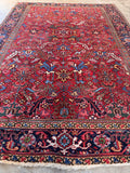 An antique red wool area rug featuring a classic Northwest Persian Heriz design.