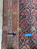 Handwoven antique rug with low pile and professional patch repairs.