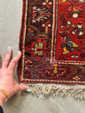 Detailed corner view of antique workshop rug with floral vines and ivory pops with some minor wool loss.