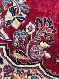 Rich red vintage Persian accent rug close up showing deep red field and botanical motifs.