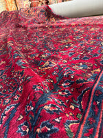 Deep jewel-toned Persian rug shown in natural light.