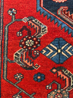 Detail of rose red field with Herati and geometric motifs.