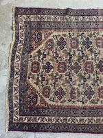 Tribal Persian rug with faded earthy neutrals and soft purple hints.