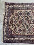 Tribal Persian rug with faded earthy neutrals and soft purple hints.