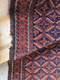 Lattice pattern Baluch rug close-up detail highlighting diamond medallions surrounded by traditional fish symbols.