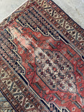 Hand-knotted antique wool rug from circa 1910 showing scattered wear and authentic age-worn texture.