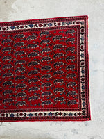 Red Persian rug with small floral motifs along the border.