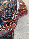 Vintage Caucasian runner featuring red border and symbolic motifs.