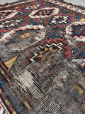 Close view of worn field on antique Kazak rug showing tribal medallion pattern.