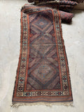 Antique Persian Baluchi tribal runner with three diamond medallions and earthy vegetable-dyed wool tones.