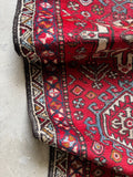 Close-up of a red karaja runner with intricate designs on a red lrbackground