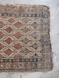 Neutral antique area rug featuring distressed low pile and geometric tribal border.