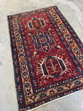 Antique 1920s Persian Heriz rug with triple medallion design and deep red field.