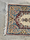 Small plush Persian accent rug with an ivory center and powder blue floral border.
