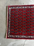 Compact vintage Persian rug with rows of paisley patterns and ivory accents.