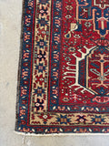 Corner view of small Persian Heriz rug with vegetable dyed wool and tribal geometric motifs.