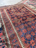 Hand-knotted nomadic wool rug with an irregular geometric tribal design.