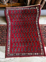Mid-20th century Persian rug featuring decorative paisley on a red ground.