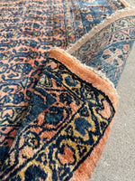 Floppy-handle Persian rug with romantic coral tones and dark blue botanical accents.