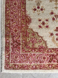 Corner view of Turkish rug featuring a soft camel and tan border with a traditional turtle motif.
