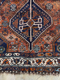 Rustic antique Persian Shiraz rug with deep navy accents and earthy warmth.