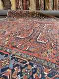 Antique Persian area rug. 1920s Heriz carpet with bold tribal artwork, sun-baked colors, and a striking midnight blue border.