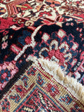 Underside of palatial antique Heriz rug with crimson, ivory, sage, and teal color palette.