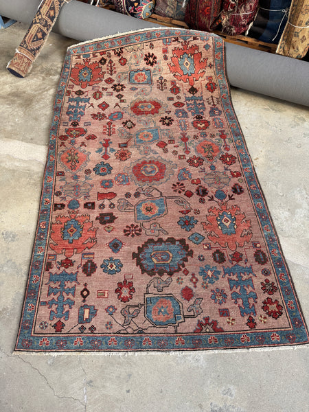 Vintage Persian Heriz rug with blush ground and angular medallions.