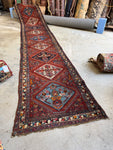 Full view of an 18-foot vintage Persian Heriz runner on display.