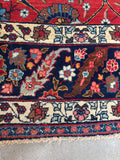 Antique Persian rug with navy border and intricate botanical pattern.