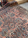 Antique Persian Rug handmade in the 1930s with a rare coral field, floral pattern, and durable wool construction.