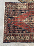 Antique Persian rug with a bold lightning bolt medallion motif and intricate geometric borders.