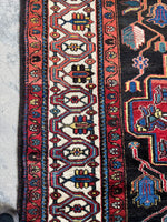 Border detail showing graphic tribal motifs on ivory ground.