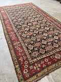 Antique Caucasian rug on charcoal field with linked lattice movement.