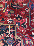 Close up view of geometric Persian Heriz carpet with warm crimson, saffron, teal, and olive tones.